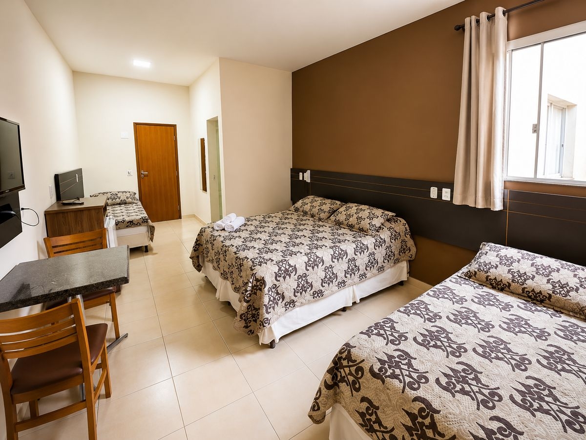 Quarto amplo com duas camas de casal, mesa de trabalho e TV