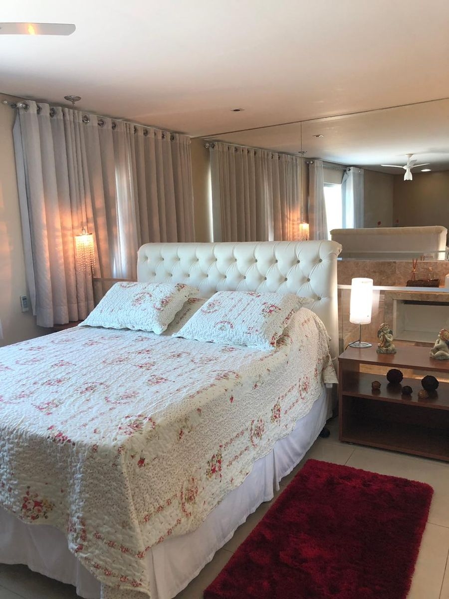Cama de casal com cabeceira estofada, colcha floral e criado-mudo
